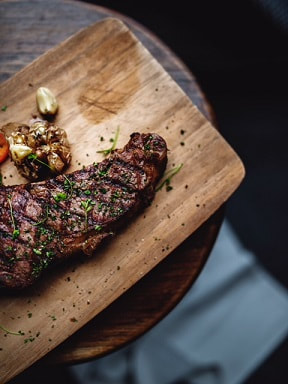 Steak and roasted garlic on wooden board