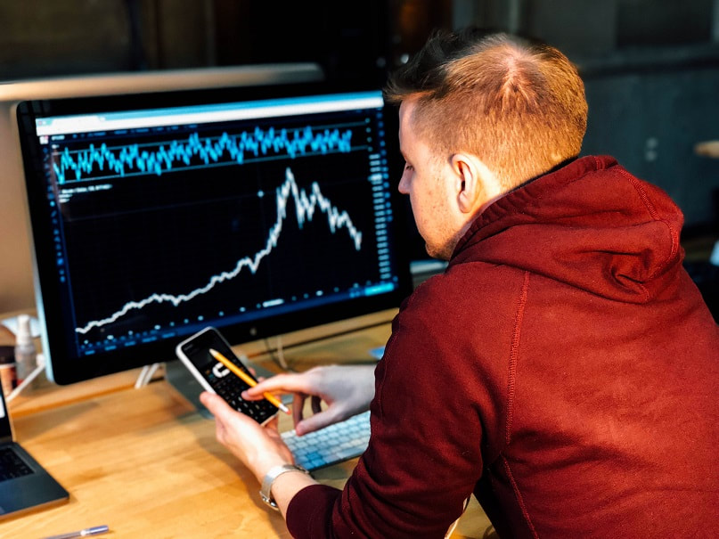 Investor sitting in front of a PC showing a stock chart